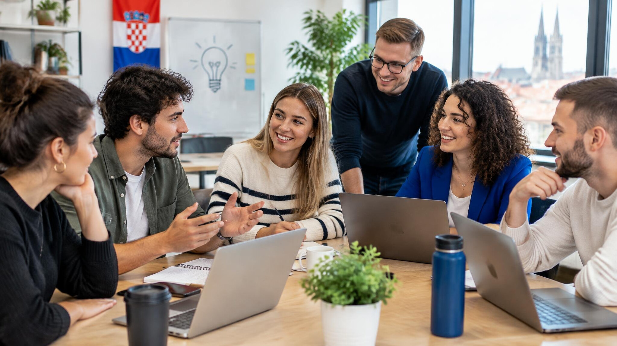 Group of young people discussing at a table with laptops